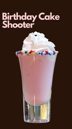 a birthday cake shooter is in a glass with whipped cream and sprinkles