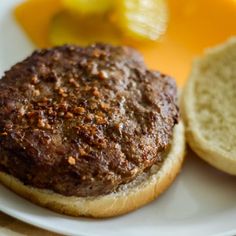 a close up of a hamburger on a plate with bread and lemons in the background