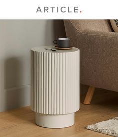 a white vase sitting on top of a wooden floor next to a chair and rug