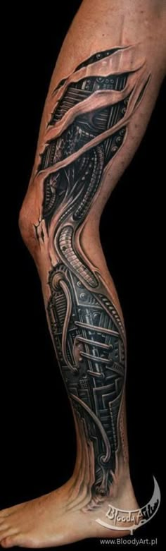 a man's leg with a black and grey tattoo design on the side of his leg