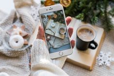 a person holding a cell phone in front of a table with coffee and christmas decorations