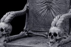 two skulls sitting on top of a chair with an intricate back and arms around them