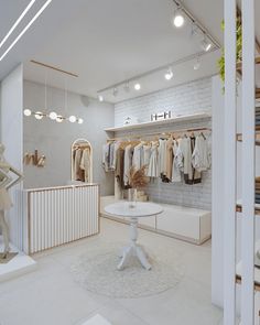 a white room with clothes on hangers and other items in the closet, along with a round table