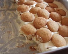 a close up of a cake in a pan with white frosting and toppings