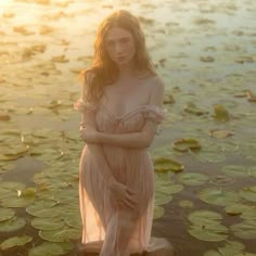 a woman is standing in the water with lily pads