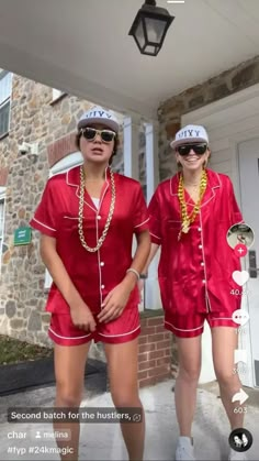 two women in matching red pajamas and hats standing on the front porch of a house