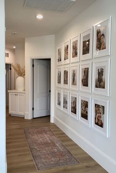 a hallway with pictures on the wall and a rug in front of an open door