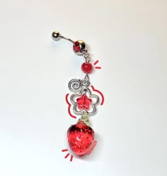 a red and silver heart belly ring on a white surface with beads around the bead