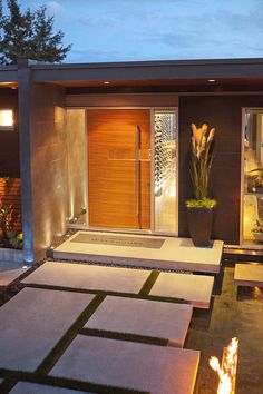 an image of a modern house at night with lights on the front door and steps leading up to it