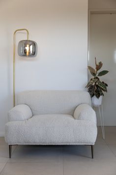 a white couch sitting next to a lamp on a wall