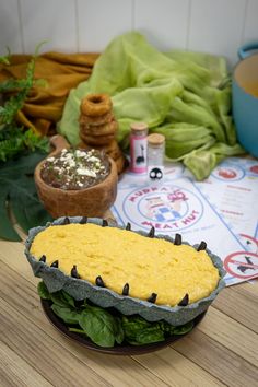 a bowl filled with food sitting on top of a wooden table next to other foods