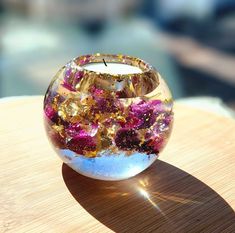 a glass candle holder sitting on top of a wooden table next to a water fountain