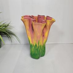 a colorful vase sitting next to a potted plant