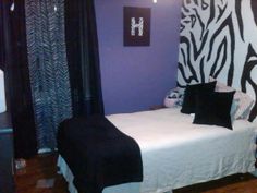 a bedroom with zebra print on the wall and purple walls, white bedding and black curtains