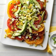 a white plate topped with tomatoes, avocado and corn on top of it