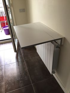 a white table sitting on top of a tiled floor next to a door and window