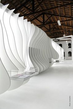 the interior of a building with white walls and wood ceilinging is lined with wavy lines