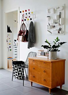 a wooden dresser sitting next to a wall mounted potted plant on it's side