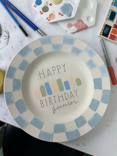 a birthday plate with the words happy birthday written on it next to paintbrushes