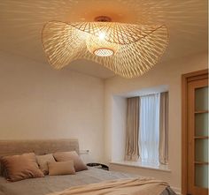 a bed room with a neatly made bed and a light fixture hanging from the ceiling