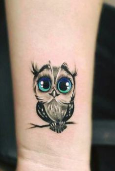 an owl with big blue eyes on the wrist is shown in this tattoo style photo