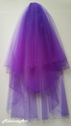 a purple tulle skirt hanging on a wall with the bottom layer pulled up to show it's layers