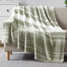 a green and white blanket sitting on top of a couch next to a potted plant