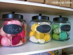 three jars filled with balls of yarn on top of a shelf