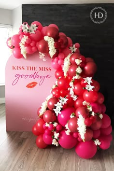 Pastel pink party panel backdrop with "Kiss the Miss" in a red serif font, "goodbye" in a magenta script font" and "#henparty" in a white script font. Illustration of red lips. The party panel is decorated with an impressive balloon arch made up of different sized red and pink balloons. Bachelorette Party Backdrop, Bachelorette Party Essentials, Hen Party Balloons, Bridal Shower Table Decorations, Retro Bridal Showers, Red Party Decorations, Bachelorette Balloons, Bridal Shower Balloons