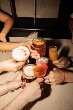 several people are toasting with drinks in front of each other on a counter top