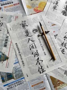 newspapers with chinese writing and a pen on top of them, all covered in newspaper clippings