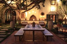 an outdoor dining area is lit up with candles on the table and benches around it