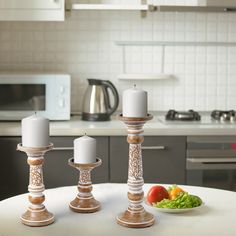 three candles sitting on top of a table next to a plate of vegetables and fruit