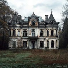 an old abandoned house in the middle of a field with tall grass and trees around it