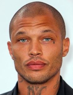 a close up of a person with tattoos on his face and chest, looking at the camera