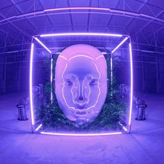 a large white mask sitting in the middle of a room filled with plants and lights