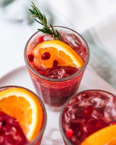 three glasses filled with cranberry and orange punch garnished with fresh rosemary