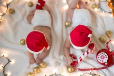 two babies wearing red and white outfits laying on a blanket with christmas decorations around them