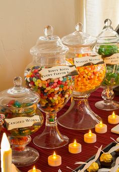 a table topped with lots of candy covered desserts next to candles and candies