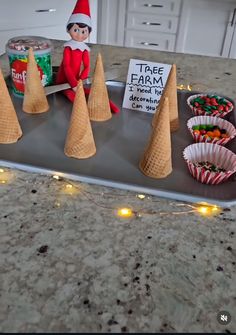 an elf is sitting on top of a tray with cones in front of him and some candy