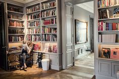 a woman sitting on a chair in front of a book shelf filled with lots of books