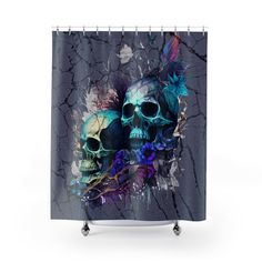 a shower curtain with two skulls and flowers on the front, one skull is painted in blue