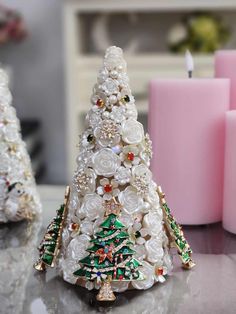 a small christmas tree made out of buttons and beads on a table next to candles