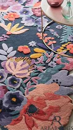 an area rug with flowers on it and a table next to it in the background