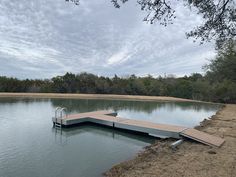 a dock sits in the middle of a body of water with trees and grass around it