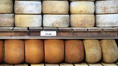 several cheeses are stacked on shelves in a store