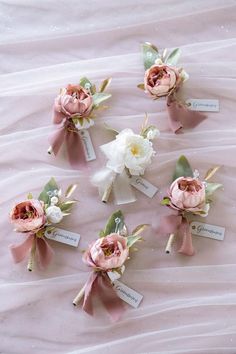 pink and white flowers are arranged on a bed sheet with name tags attached to them