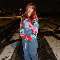 a woman standing in the snow holding a knife and wearing overalls with her hands on her hips