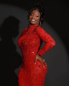 a woman in a red dress posing for the camera with her hands on her hips