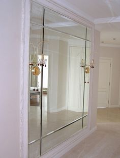 a large mirror in the middle of a room with white walls and flooring on either side